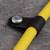 Un câble jaune est fixé avec un clip de câble noir sur une surface grise. Une vis métallique est visible en haut.