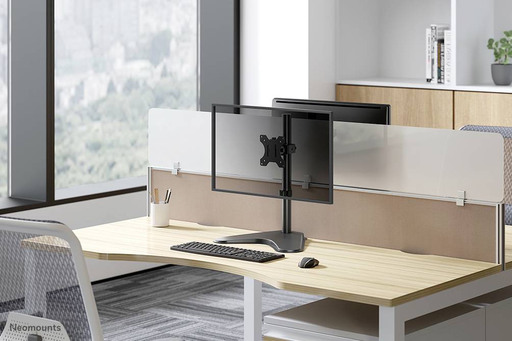 Un espace de bureau moderne avec un bureau, deux écrans sur un support, un clavier et une souris. La fenêtre en arrière-plan offre une vue sur la ville.