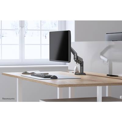 Un bureau moderne avec un bureau, un moniteur sur support, un clavier et une souris. De grandes fenêtres à l'arrière-plan laissent entrer la lumière.
