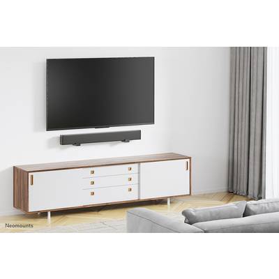 Un salon avec un téléviseur monté au mur au-dessus d'une barre de son. En dessous se trouve un meuble TV moderne et minimaliste.
