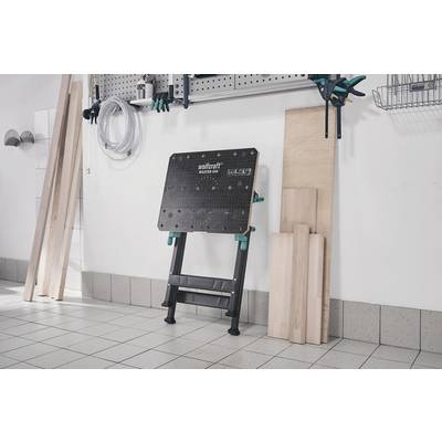 'Poste de travail dans un atelier avec établi et matériaux en bois contre le mur.'