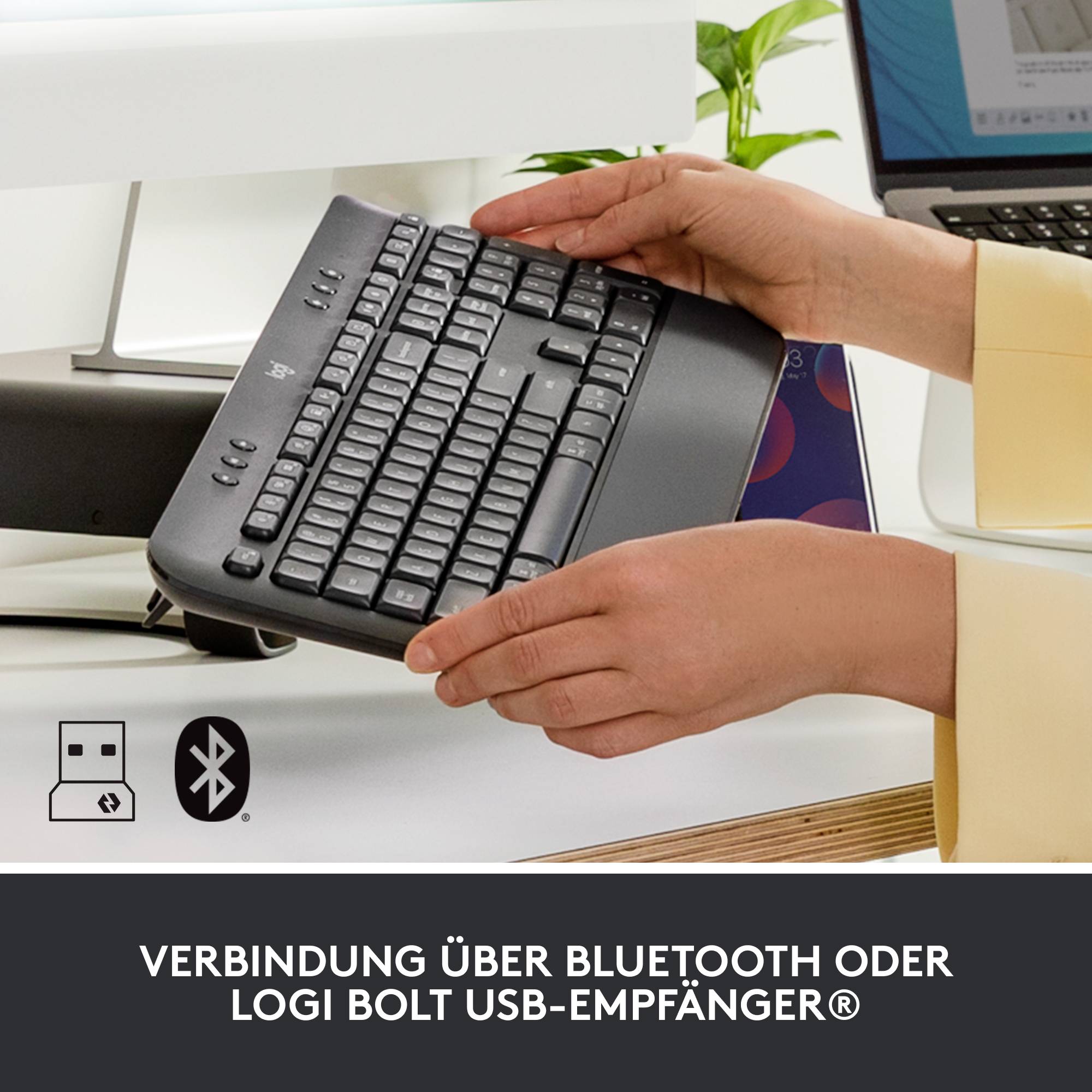 'Gros plan sur des mains tenant un clavier. Possibilités de connexion via Bluetooth ou récepteur USB Logi Bolt.'