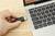 Une personne branche un câble HDMI dans un ordinateur portable posé sur une table en bois. L'ordinateur portable est ouvert, affichant son clavier.