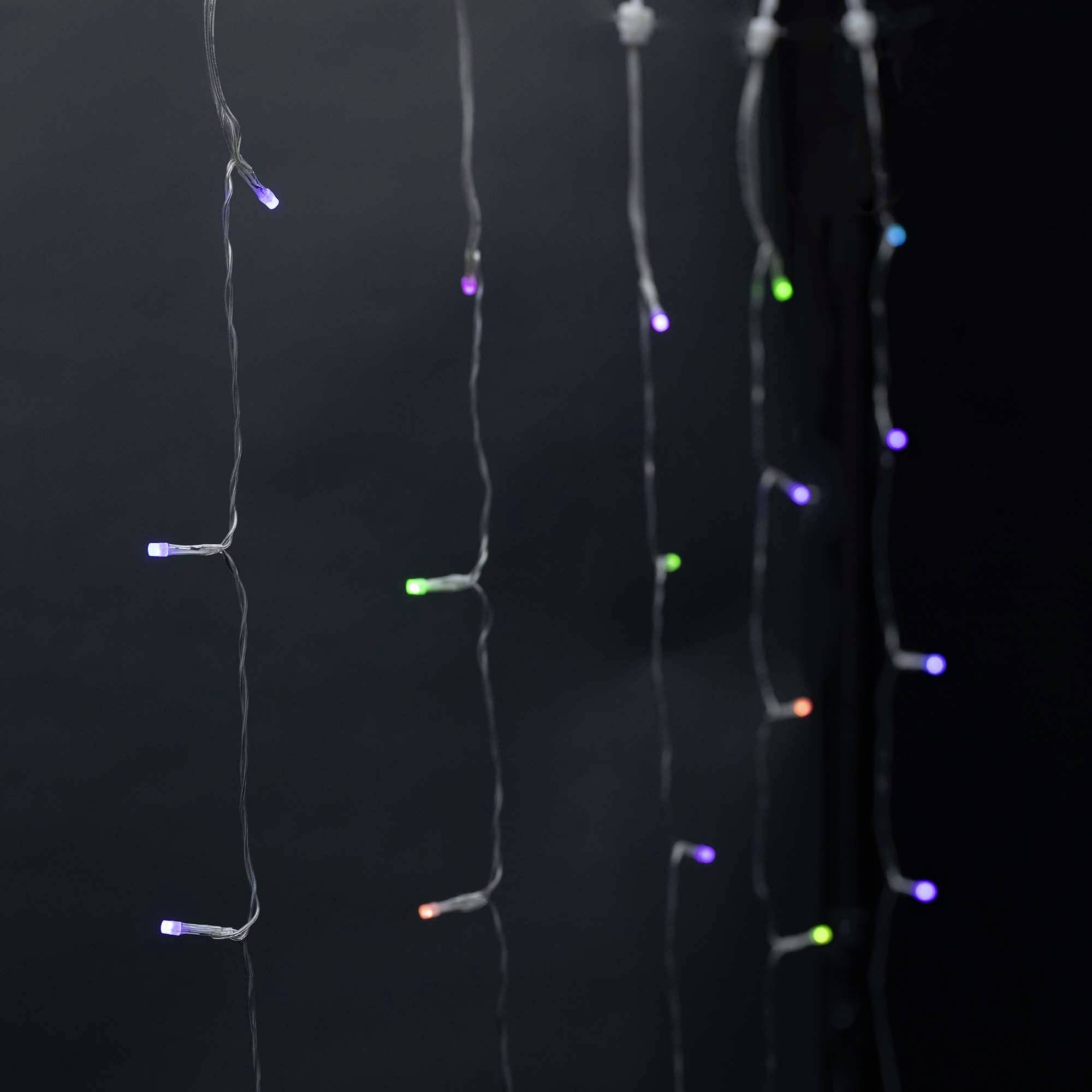 Plusieurs rangées de guirlandes lumineuses LED suspendues dans différentes couleurs contre un fond sombre.