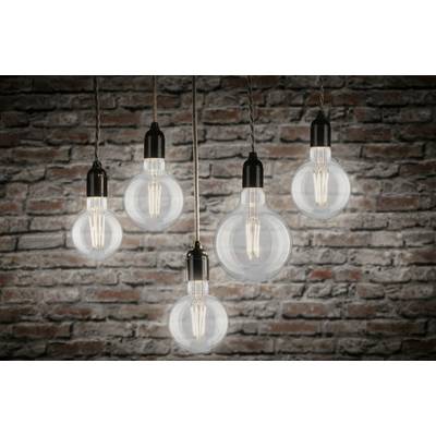 Cinq ampoules élégantes sont suspendues devant un mur de briques, illuminant la pièce et créant une atmosphère chaleureuse et accueillante.