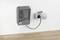 Chargeur de batterie sur un mur blanc, branché à une prise électrique. L'appareil dispose de plusieurs emplacements de charge et est destiné à un usage intérieur.