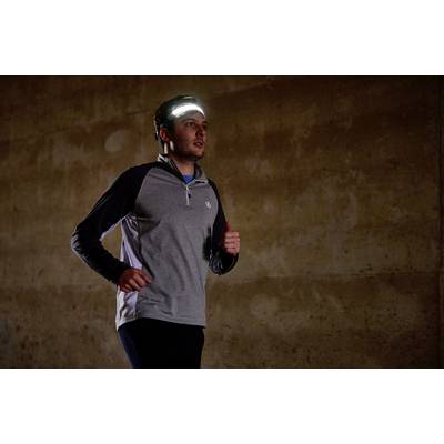 Un homme fait du jogging dans une pièce sombre, portant un t-shirt à manches longues et un bandeau frontal qui éclaire son environnement.
