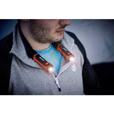 Un homme porte une veste grise et une lampe LED autour du cou. La lampe est orange et brille dans deux directions.
