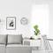 Un salon moderne avec un canapé gris, une horloge au mur, une étagère blanche et des plantes d'intérieur. Un aménagement lumineux et minimaliste.