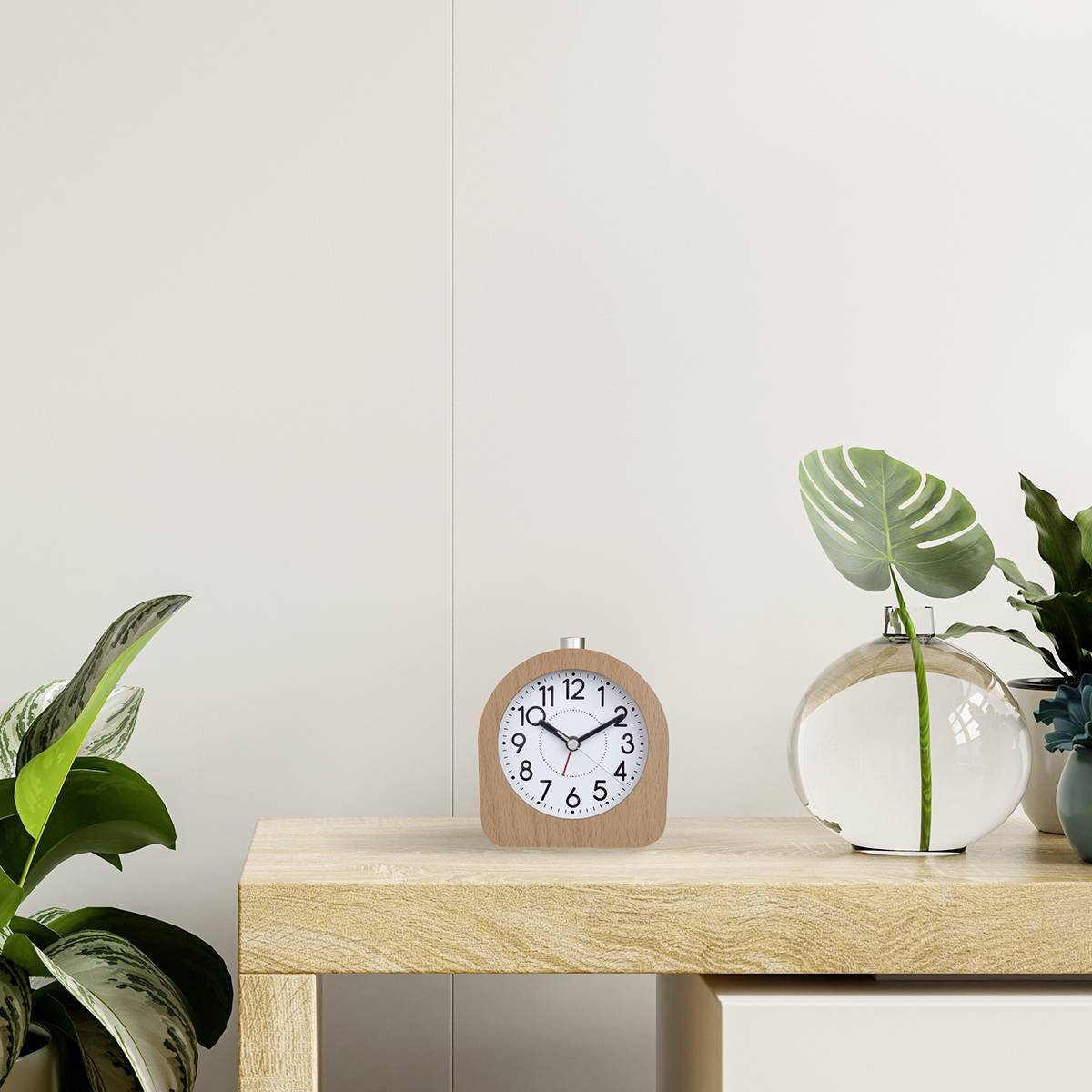 Un espace minimaliste avec une table en bois sur laquelle sont posés un réveil, un vase avec une feuille ronde et des plantes.