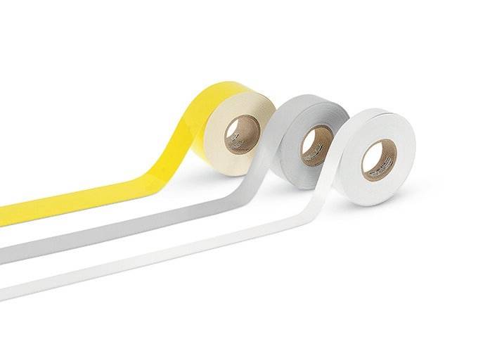 Trois rouleaux de ruban adhésif jaune, gris et blanc sont disposés côte à côte sur une surface blanche.