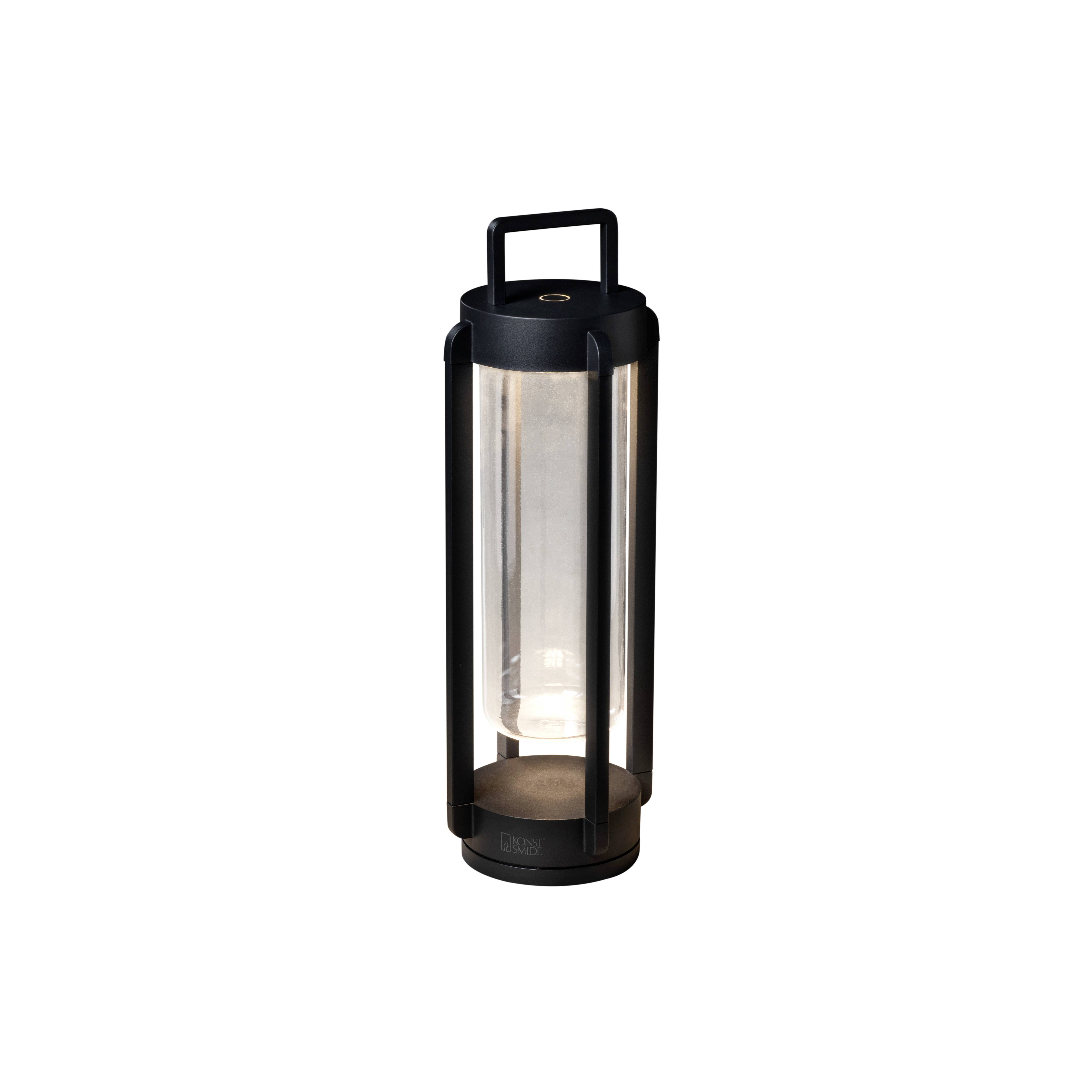 Lanterne portable noire à boîtier lisse et poignée, diffusant une lumière douce. Adaptée aux espaces intérieurs et extérieurs.
