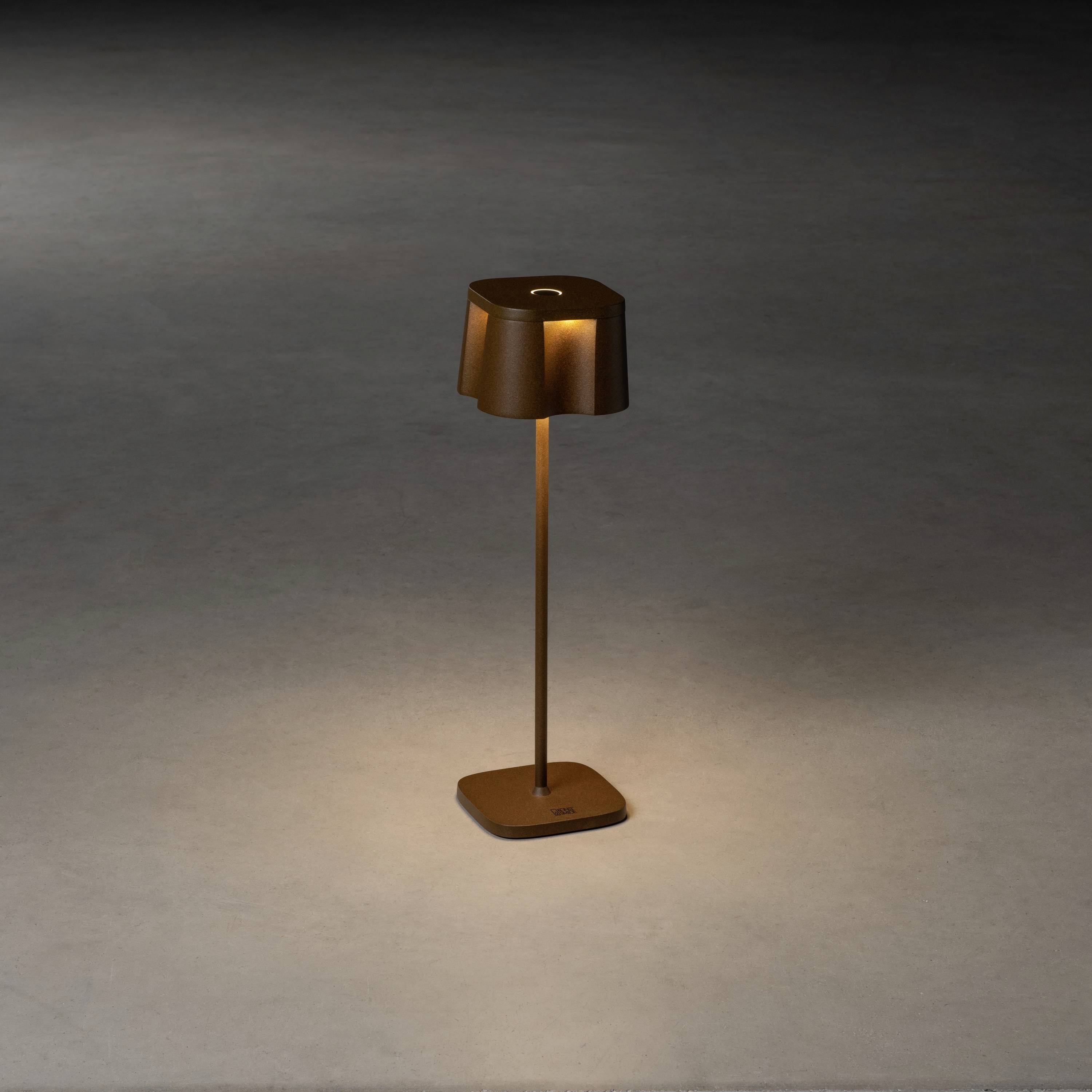 Une lampe sur pied élégante et moderne avec un abat-jour rectangulaire posée sur un sol gris, diffusant une lumière chaude vers le bas.