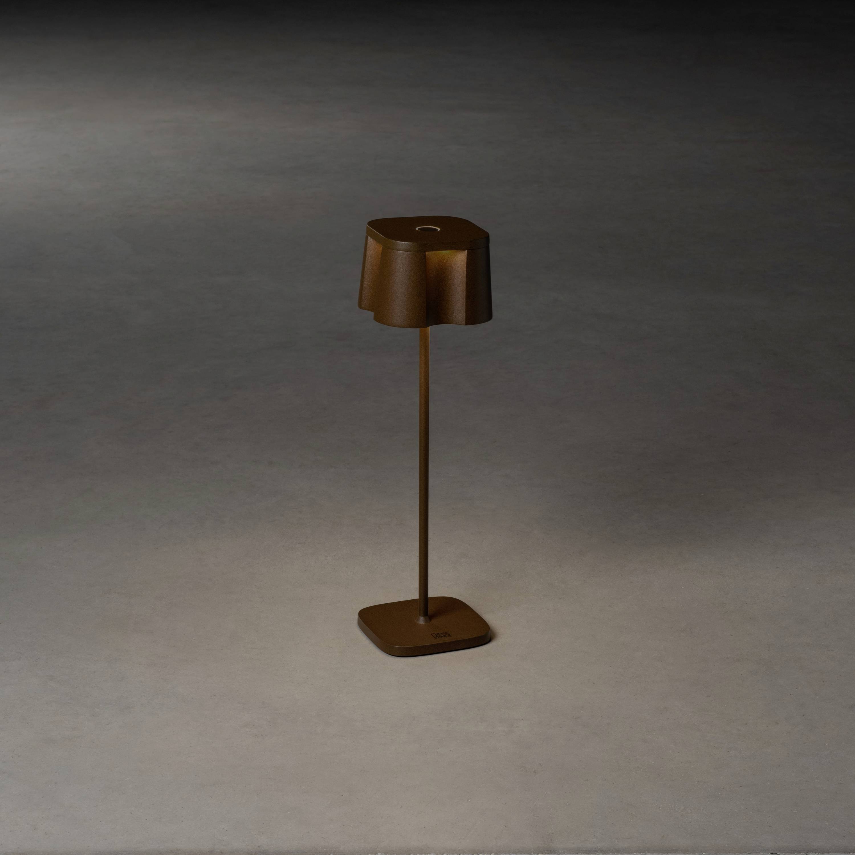 Lampadaire marron sur un sol sombre dans une pièce faiblement éclairée.