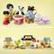 Un ensemble LEGO montre deux figurines d'enfants, un panda, une table avec des collations et un jouet de lapin. En arrière-plan, un décor urbain coloré.
