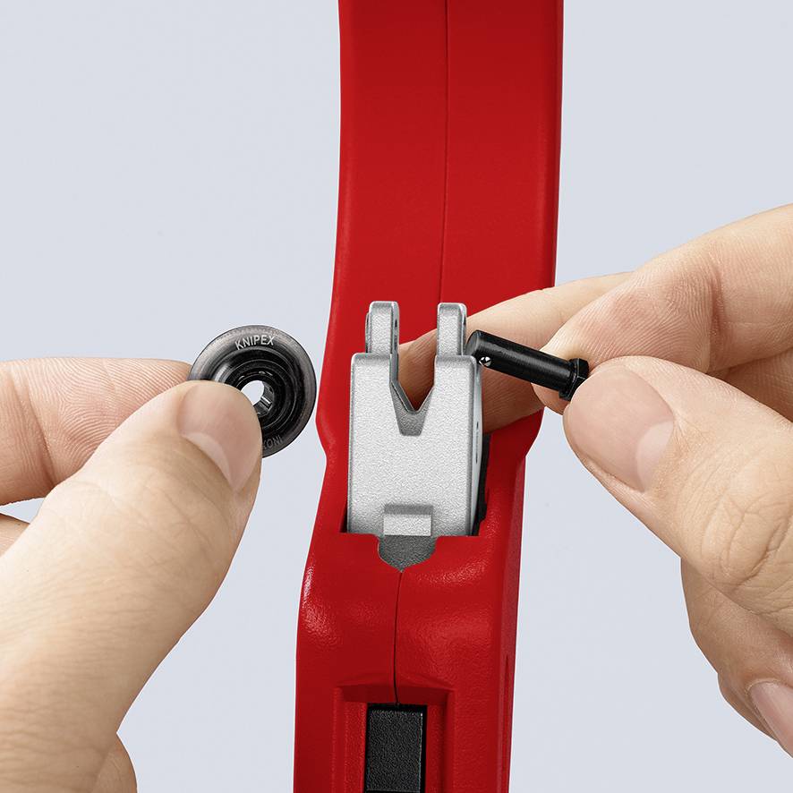 Une main montre comment un anneau de caoutchouc noir est enfilé sur une poignée d'outil rouge. L'outil comporte une partie en métal argenté.