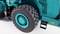 Gros plan d'un pneu gris foncé sur un véhicule turquoise, probablement un engin industriel. Certains détails sont visibles.