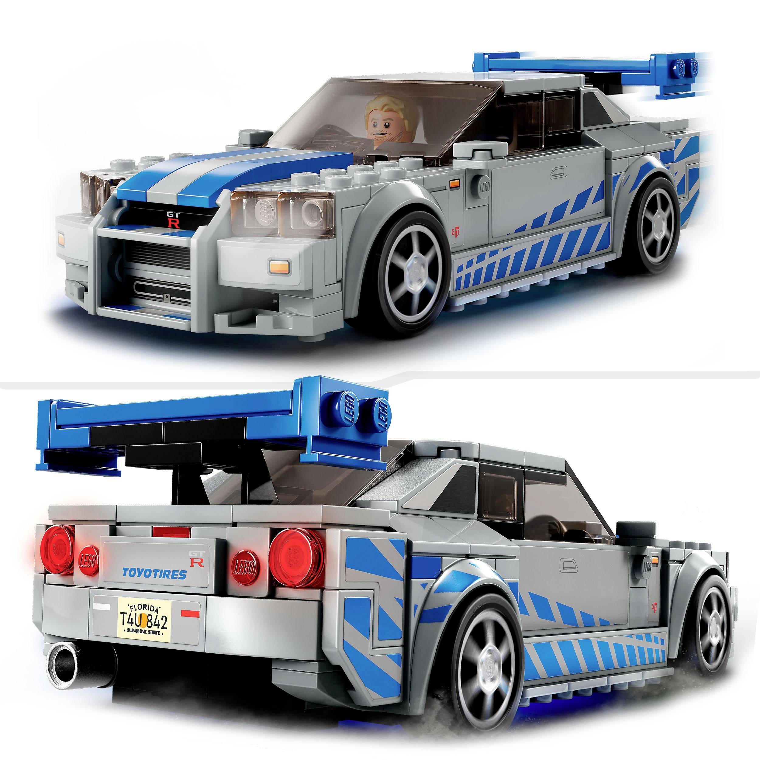 Une petite voiture de jouet grise avec des bandes bleues et un grand aileron. Une tête de figurine humaine visible à l'intérieur de la voiture.