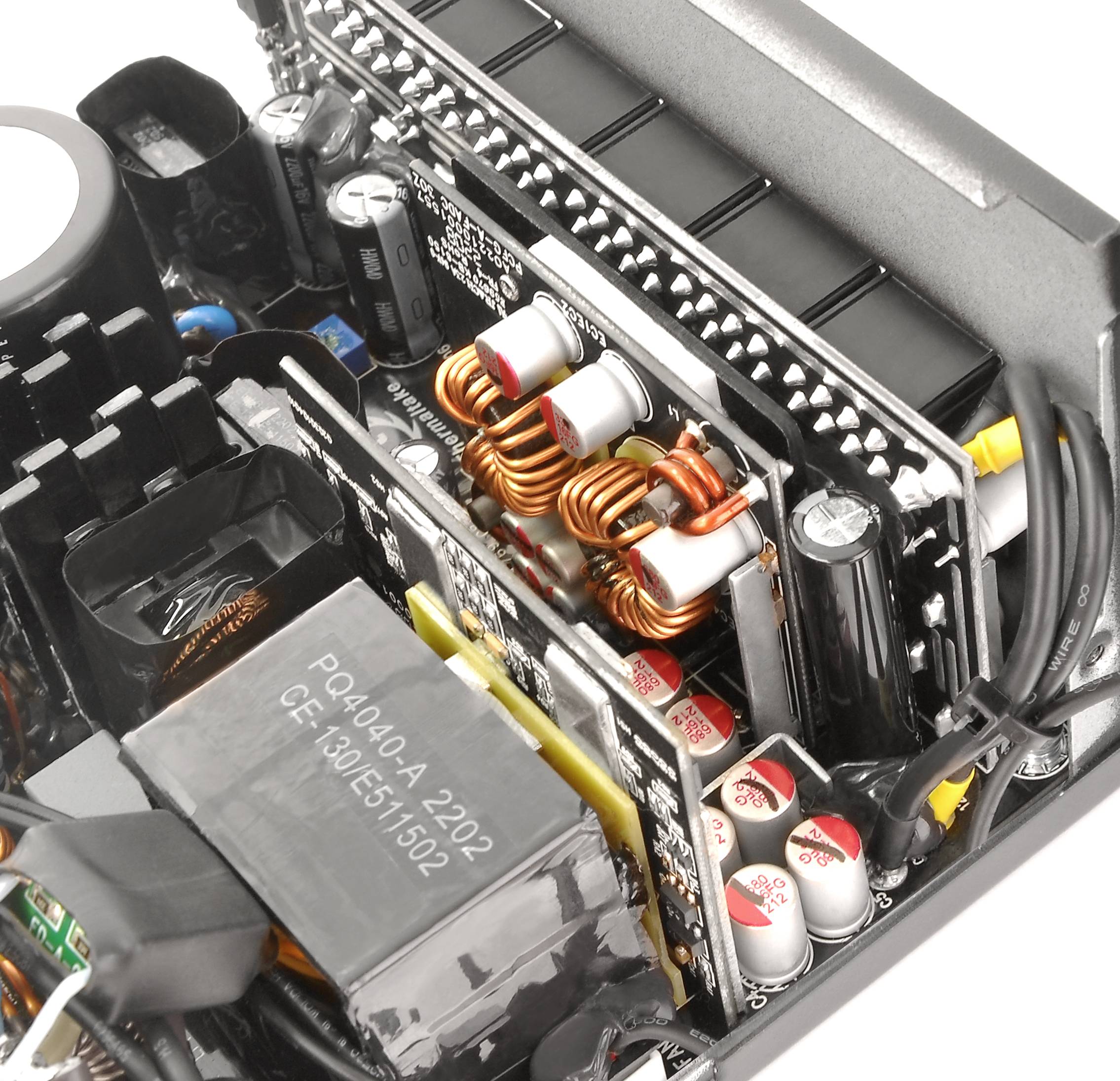 Un bloc d'alimentation d'ordinateur ouvert montre des condensateurs, des bobines et des composants de refroidissement. Les composants électroniques sont disposés de manière compacte.