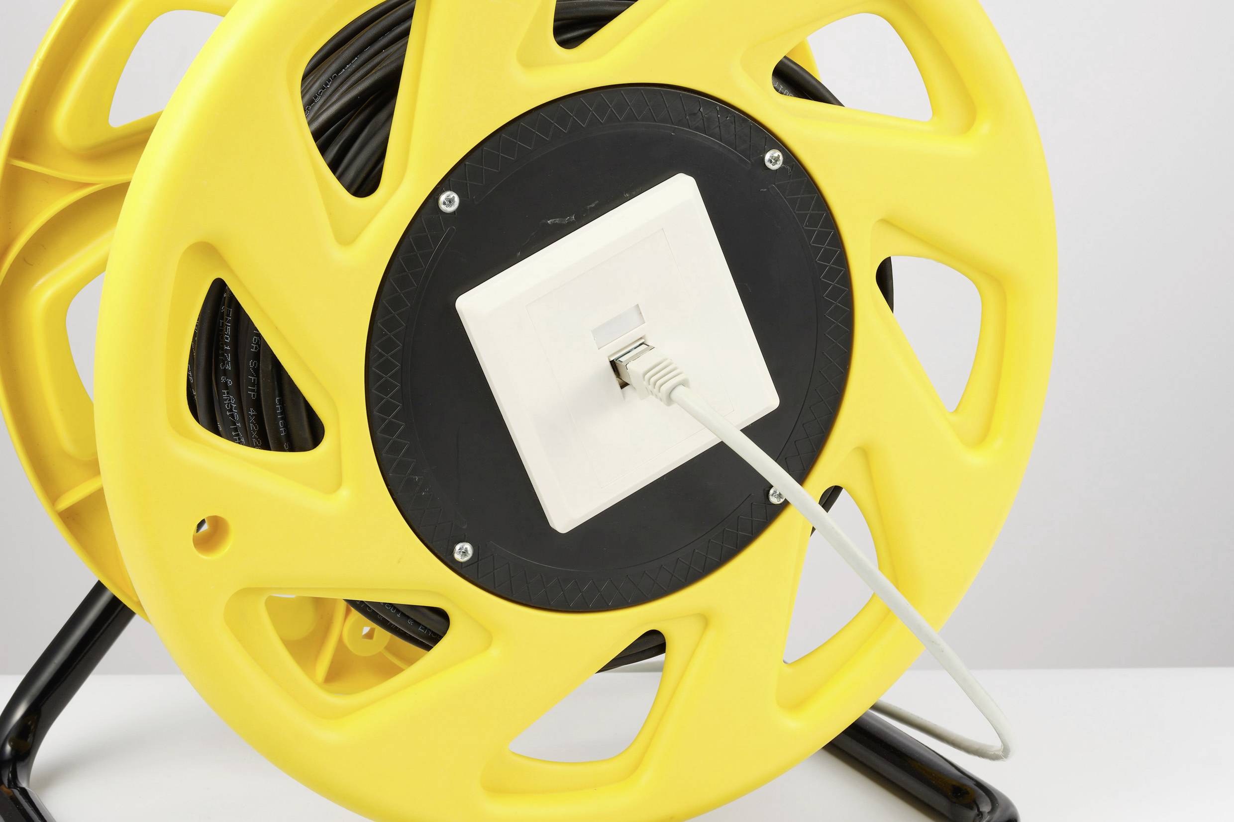 Un boîtier de tambour de câble jaune avec un câble réseau branché.