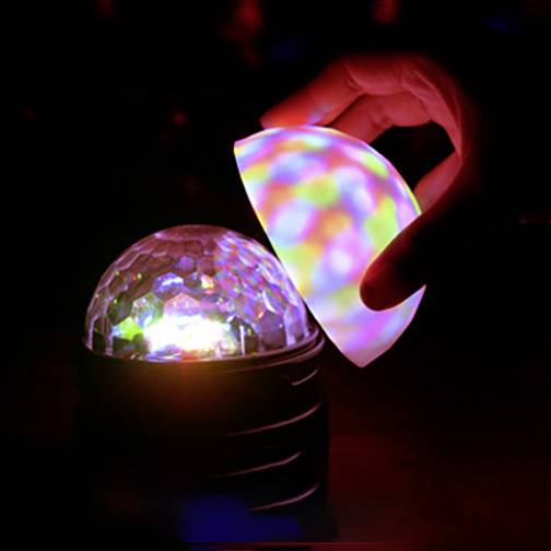 Une main tient une boule lumineuse et colorée au-dessus d'un motif hexagonal qui émet également une lumière aux couleurs vives.