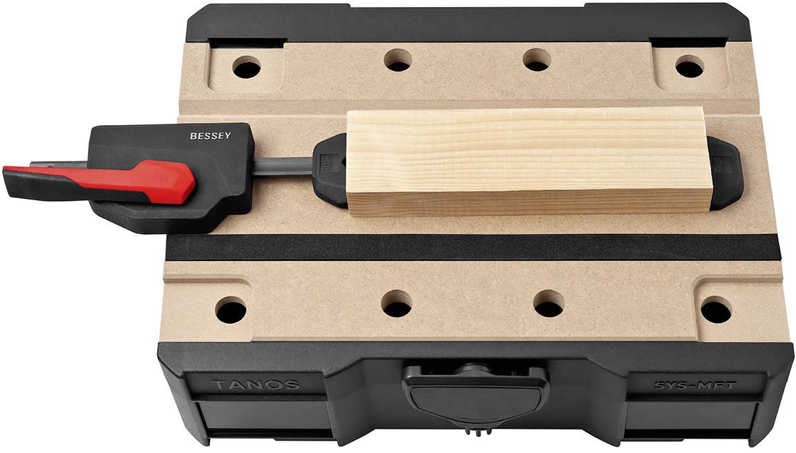Planche de bois fixée dans un serre-joint sur un établi ; un serre-joint noir et un serre-joint rouge maintiennent solidement la planche.
