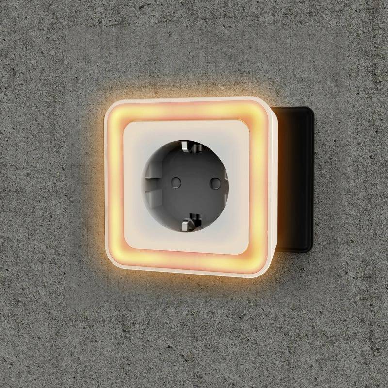 Une prise murale carrée moderne brille en orange sur un mur de béton gris. Elle sert à l'éclairage et à l'alimentation électrique avec élégance.