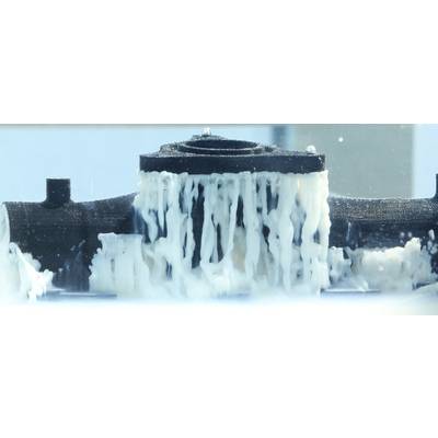 Un objet dans un appareil de test est recouvert d'un liquide, probablement pour des tests de matériau ou d'étanchéité.