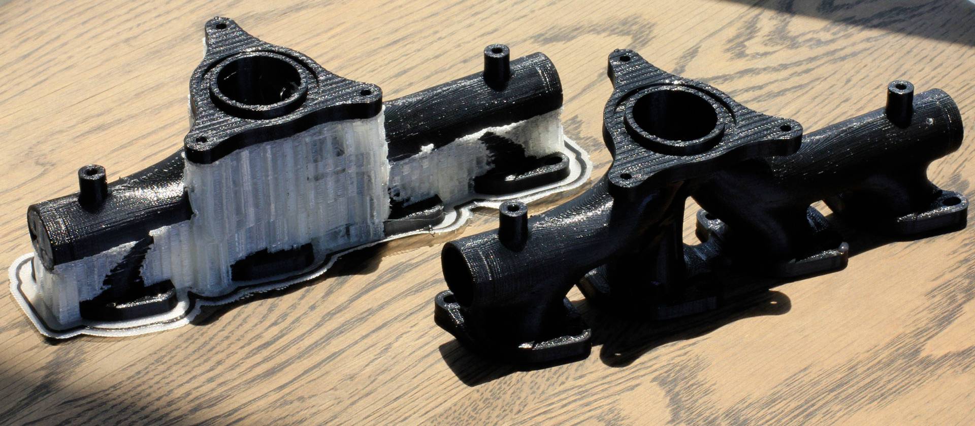 Deux pièces en plastique imprimées en 3D sur une table en bois. La pièce de gauche présente des structures de support blanches, celle de droite est achevée.