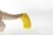 Une main touche une pièce en plastique jaune flexible, qui est courbée. L'image montre l'élasticité du matériau.