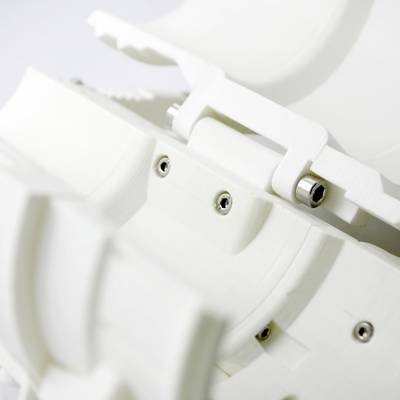 Gros plan d'une structure blanche en plastique avec plusieurs vis et articulations, probablement un composant d'un dispositif technique ou d'une machine.