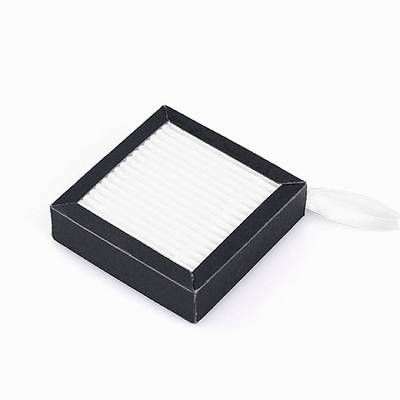 Une boîte noire carrée avec des plis blancs, probablement un filtre, est posée sur une surface blanche.