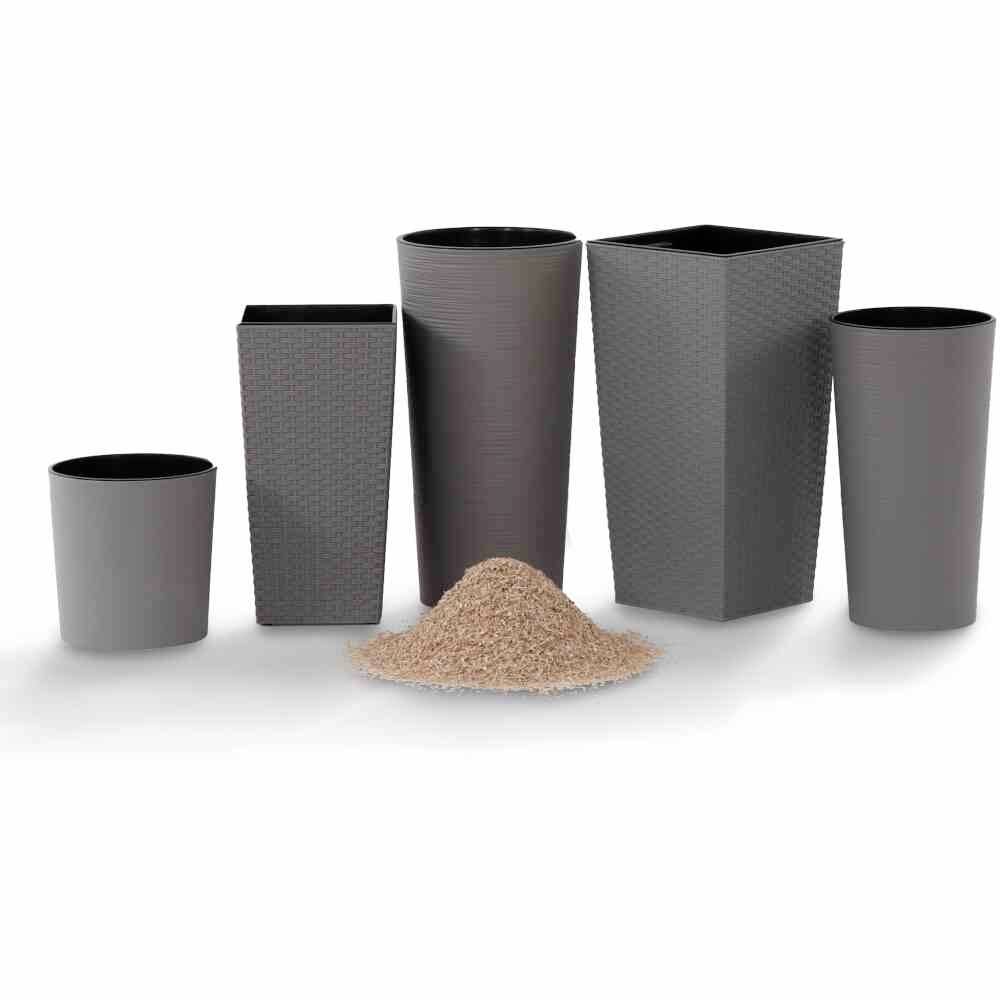 Cinq pots de fleurs en plastique gris de différentes tailles sont disposés côte à côte, avec un petit tas de sable au milieu.