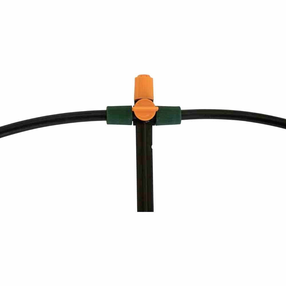 Un raccord en T d'irrigation avec une vanne de rotation orange reliant deux tuyaux noirs.
