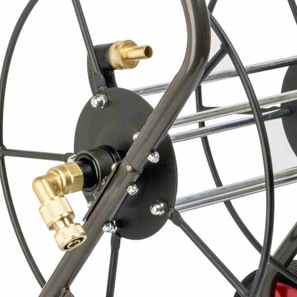 Gros plan d'un enrouleur de tuyau en métal avec des raccords et des roues, mettant en valeur son usure et sa durabilité.