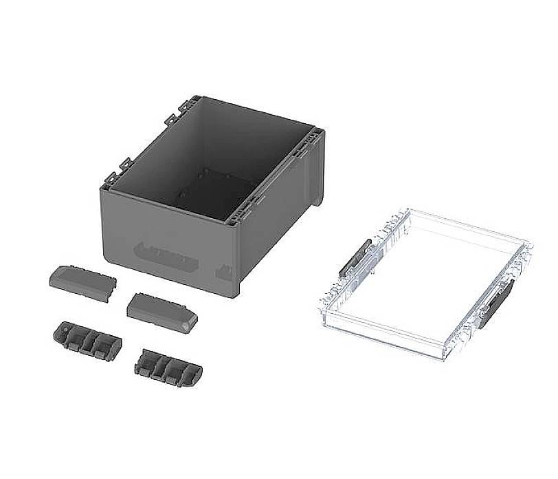 Boîte rectangulaire noire avec couvercle amovible et plusieurs éléments séparés, probablement destinée à la construction ou au rangement.