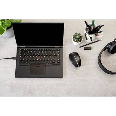 Un ordinateur portable à l'écran noir est posé sur un bureau, entouré de plantes, d'écouteurs et d'accessoires de bureau.