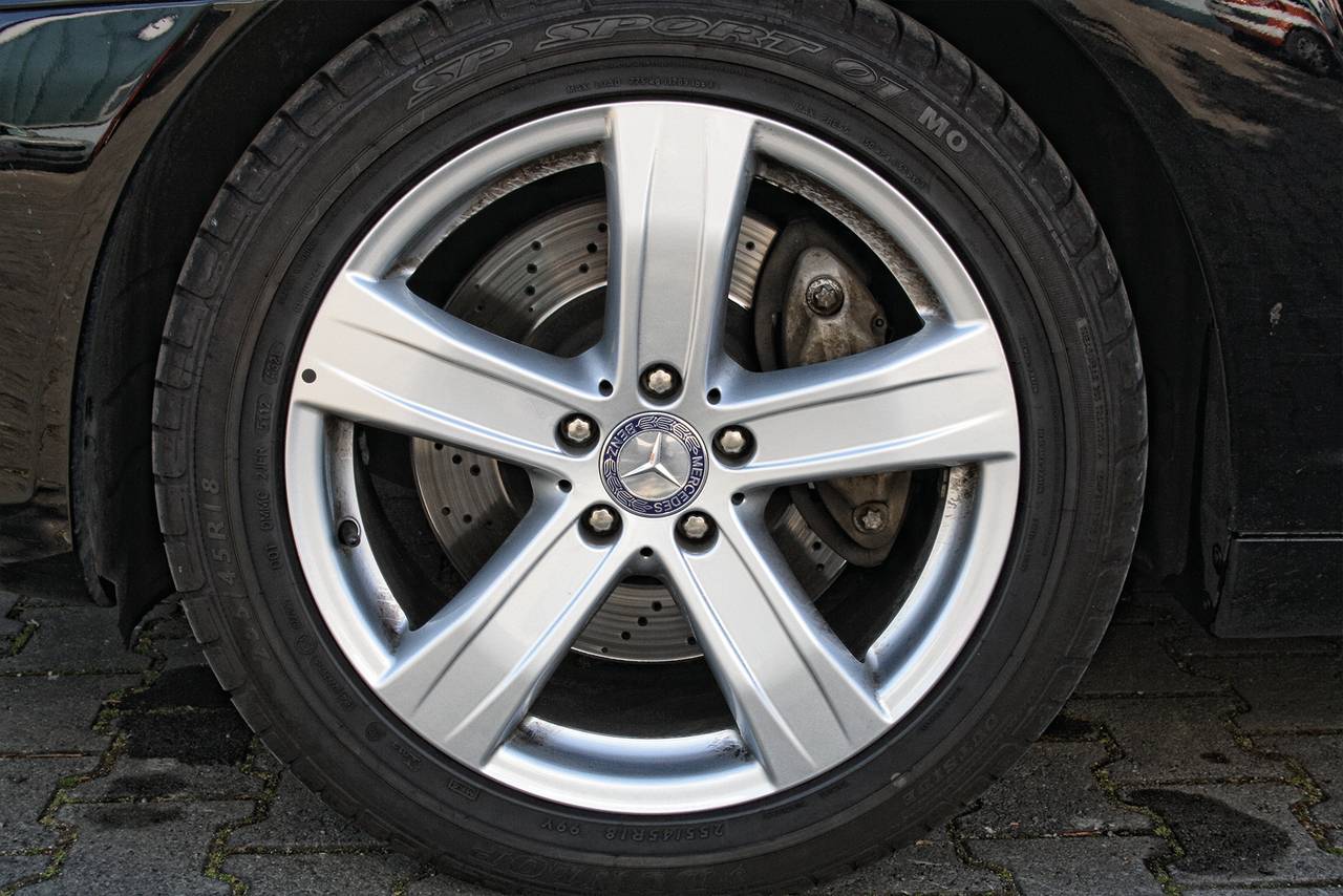 Pneu de voiture avec jante argentée et disques de frein visibles. Le pneu présente un logo en forme d'étoile au centre de la jante.