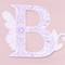 Une lettre 'B' ornementale en rose sur un fond rose pâle. Le design comprend des motifs floraux décoratifs.
