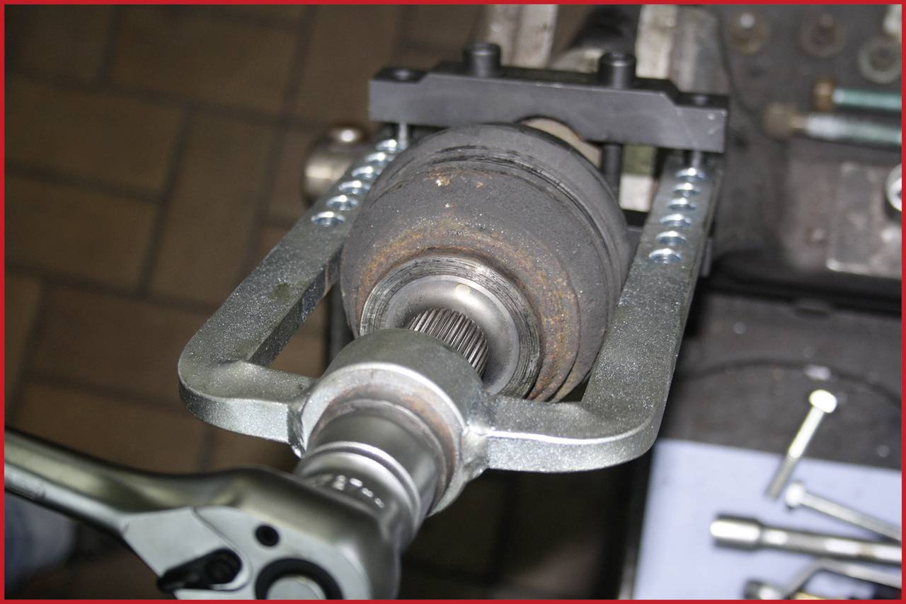 Un gros plan montre un outil de véhicule fixé à un essieu, probablement lors d'une réparation ou d'un entretien de la voiture.