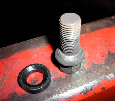 Un boulon et une rondelle sont posés sur une surface métallique brun-rouge.