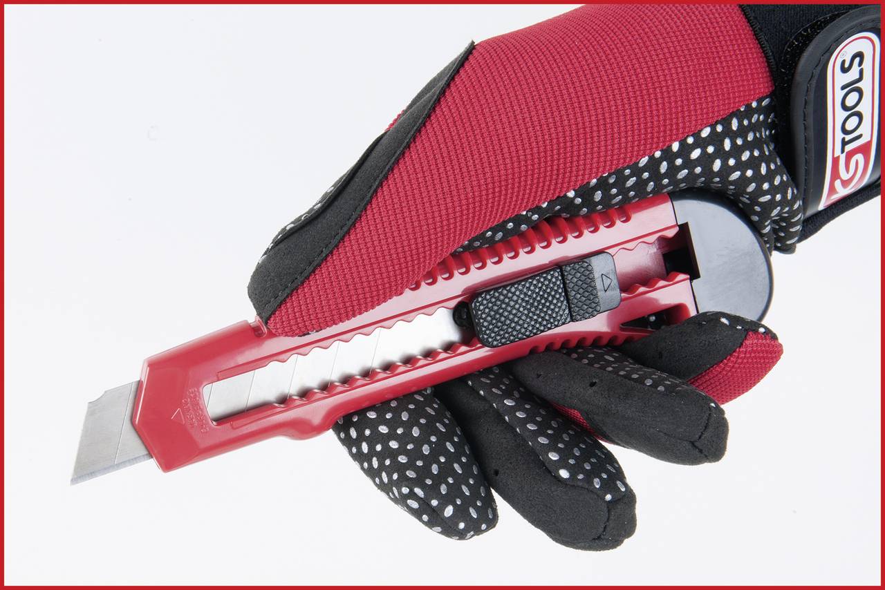 Une main gantée portant un gant à pois tient un cutter rouge avec la lame sortie.