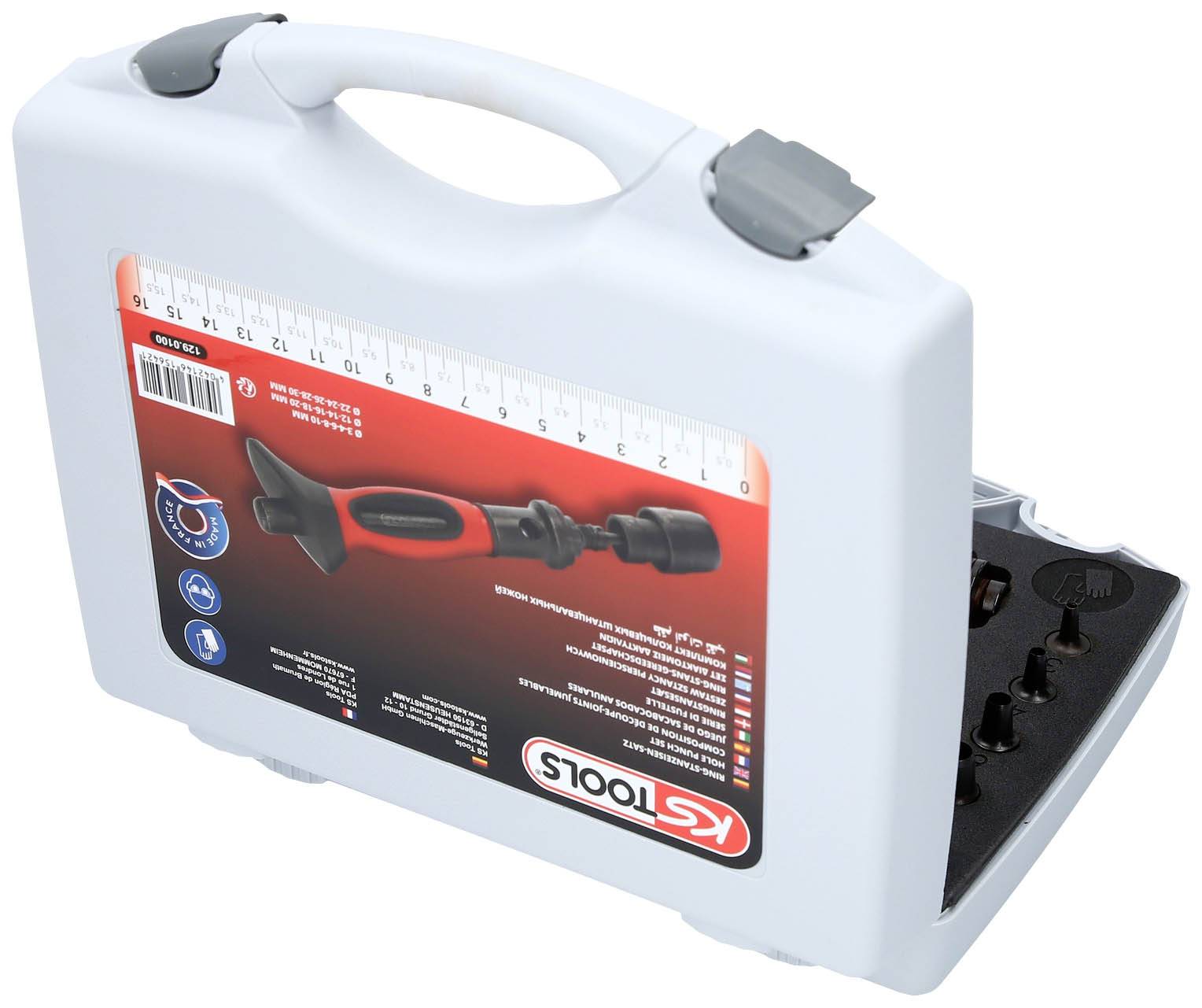 Une valise à outils grise avec une poignée de transport, sur laquelle un autocollant représente une machine rouge avec ses accessoires et des détails techniques. Ouverte, laissant apparaître ses différentes pièces.