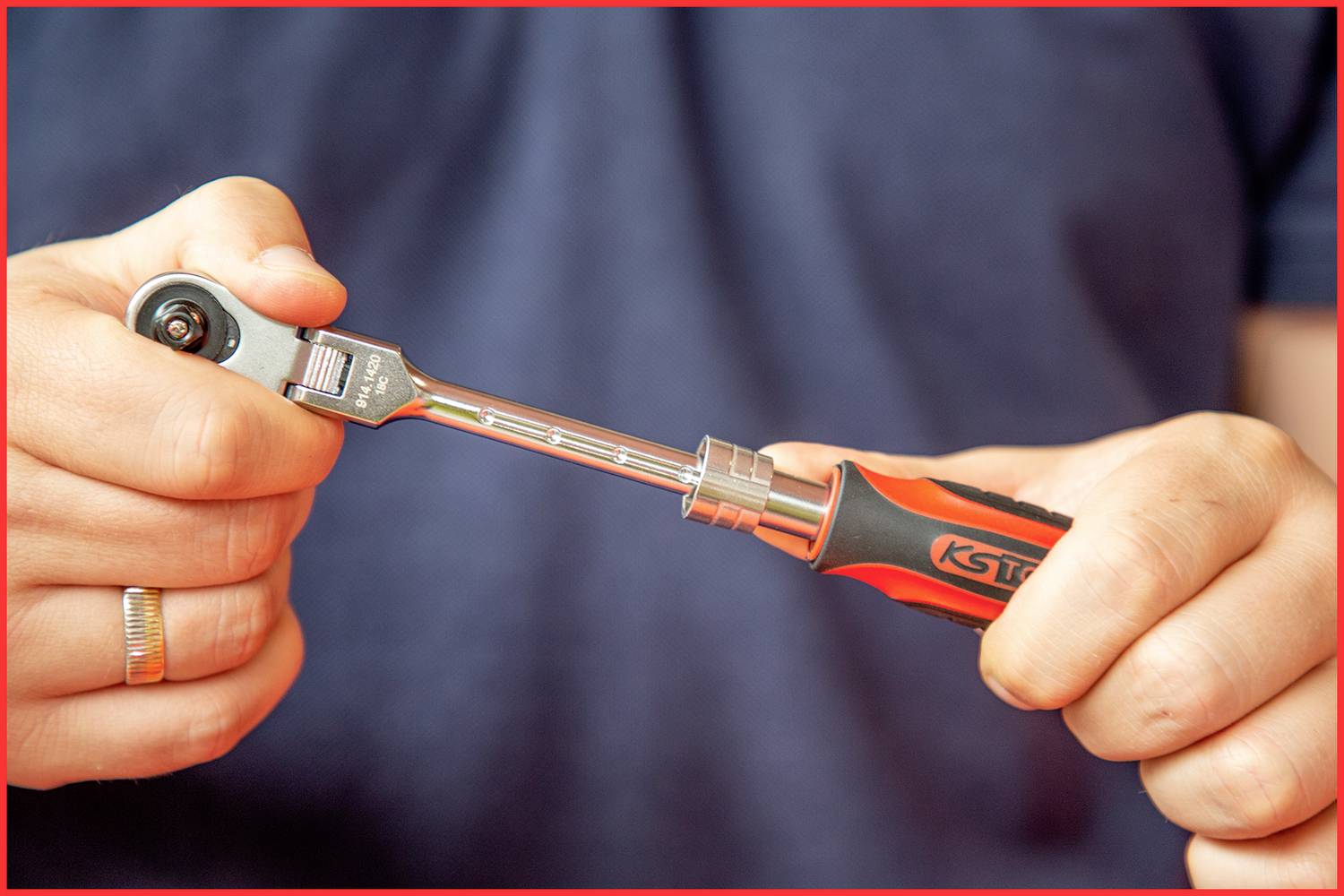 Une personne tient une clé à cliquet. Les mains sont concentrées, tandis que l'arrière-plan est flou.