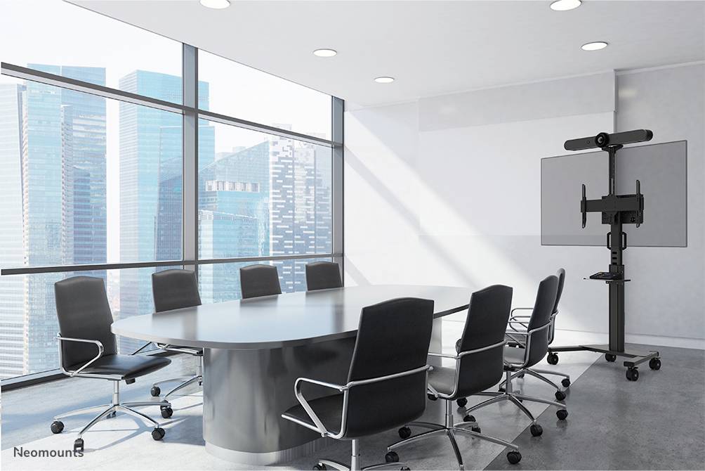 Salle de conférence avec une grande table et huit chaises, vue sur des immeubles modernes à travers de grandes fenêtres. Un écran est prêt à être utilisé.