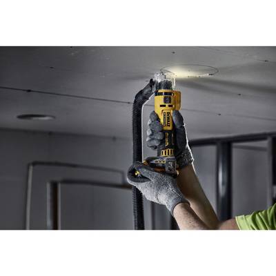 Une personne découpe un trou circulaire dans un plafond à l'aide d'un outil oscillant, portant des vêtements de protection.