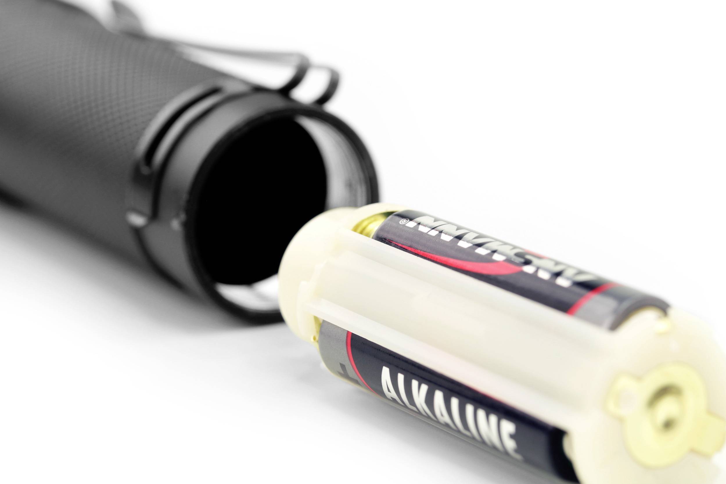 Une lampe de poche noire ouverte, avec une pile alcaline dépassant partiellement.
