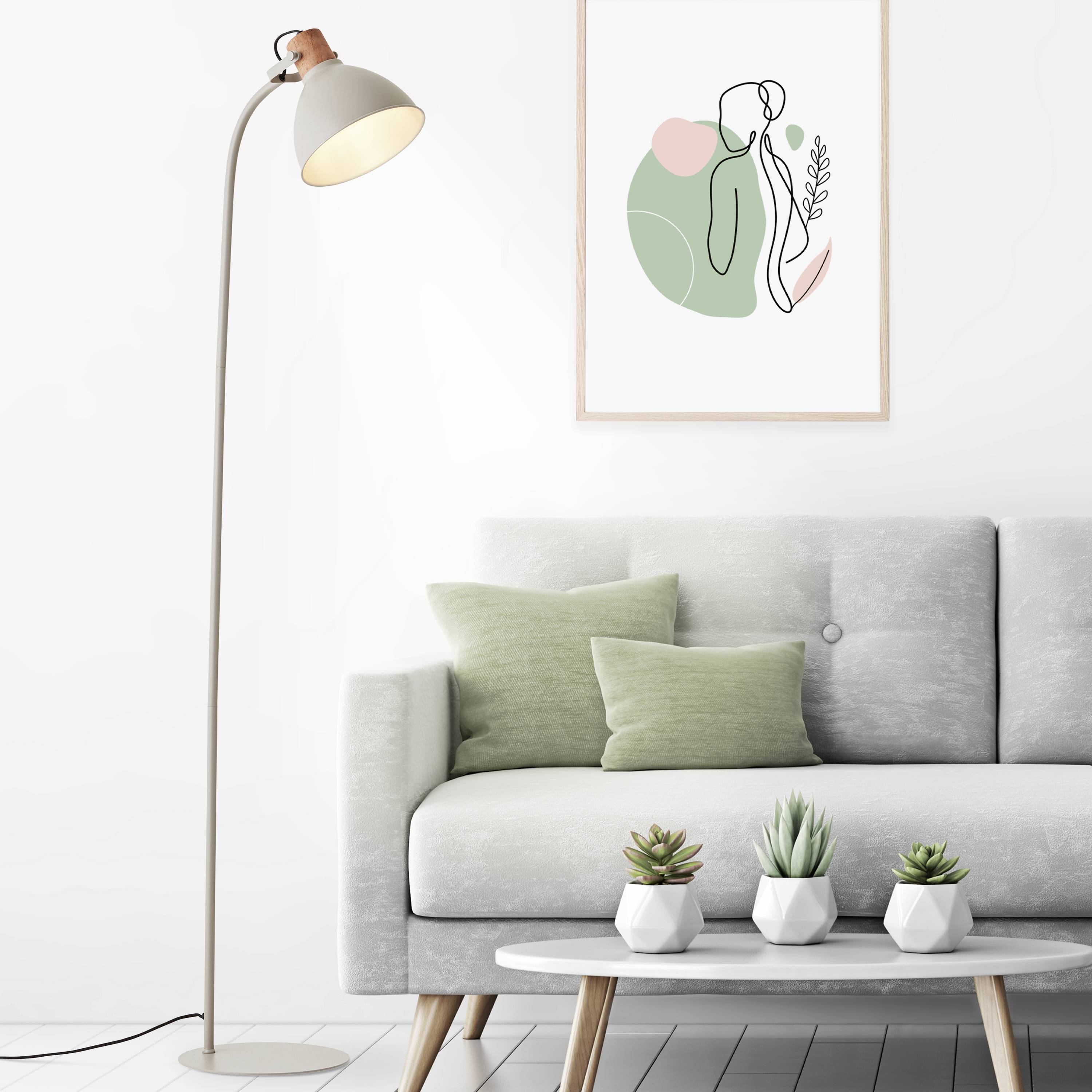 Une pièce avec un canapé gris, des coussins verts, trois petites plantes sur une table et une œuvre d'art murale moderne.