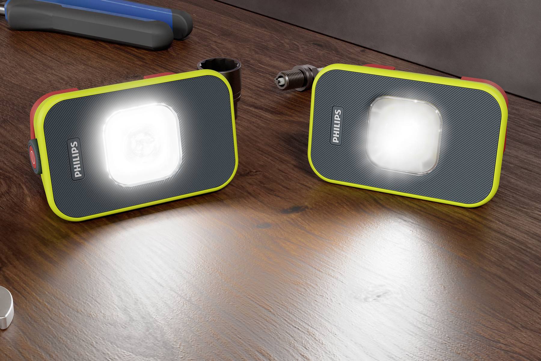 Deux lampes LED portables de Philips avec une lumière blanche brillante sur une table en bois. Elles présentent un design moderne et robuste.
