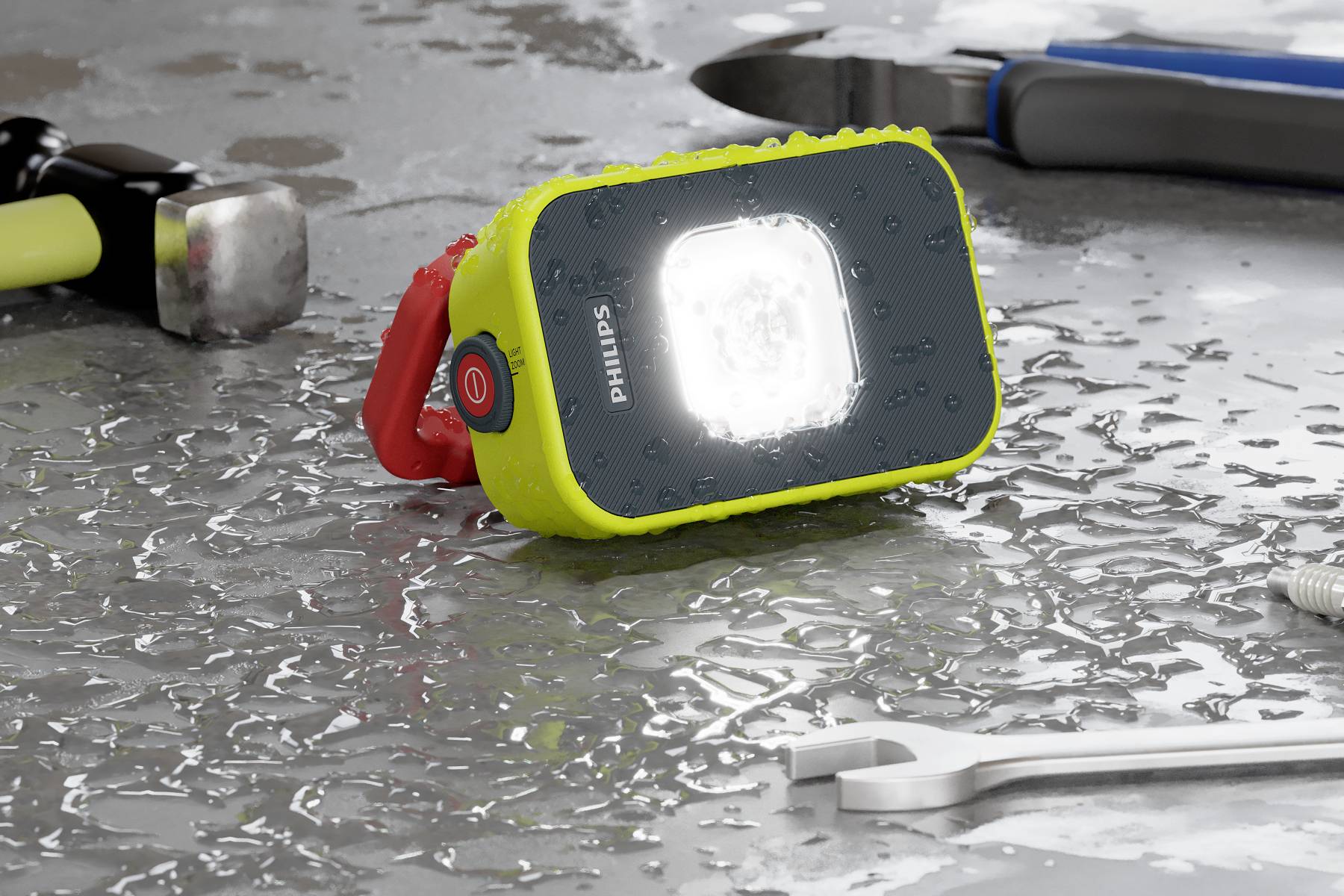 Une lampe de travail lumineuse et résistante aux éclaboussures est posée sur une table mouillée à côté d'un marteau, d'une clé à molette et d'une pince.